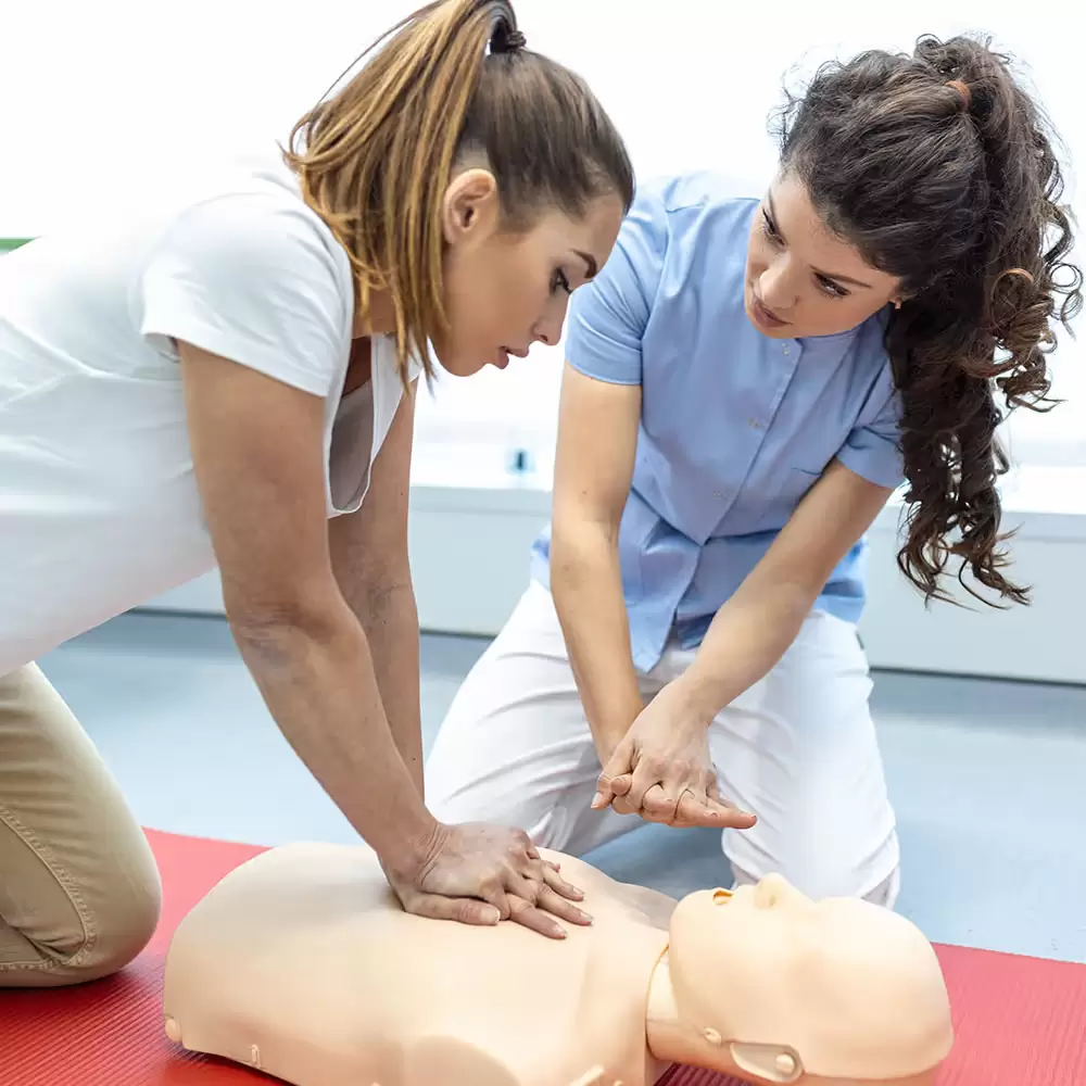 A woman being instructed on how to perform CPR on a dummy