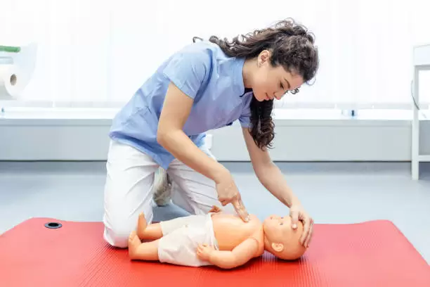 Woman performing CPR on baby training doll with one hand.